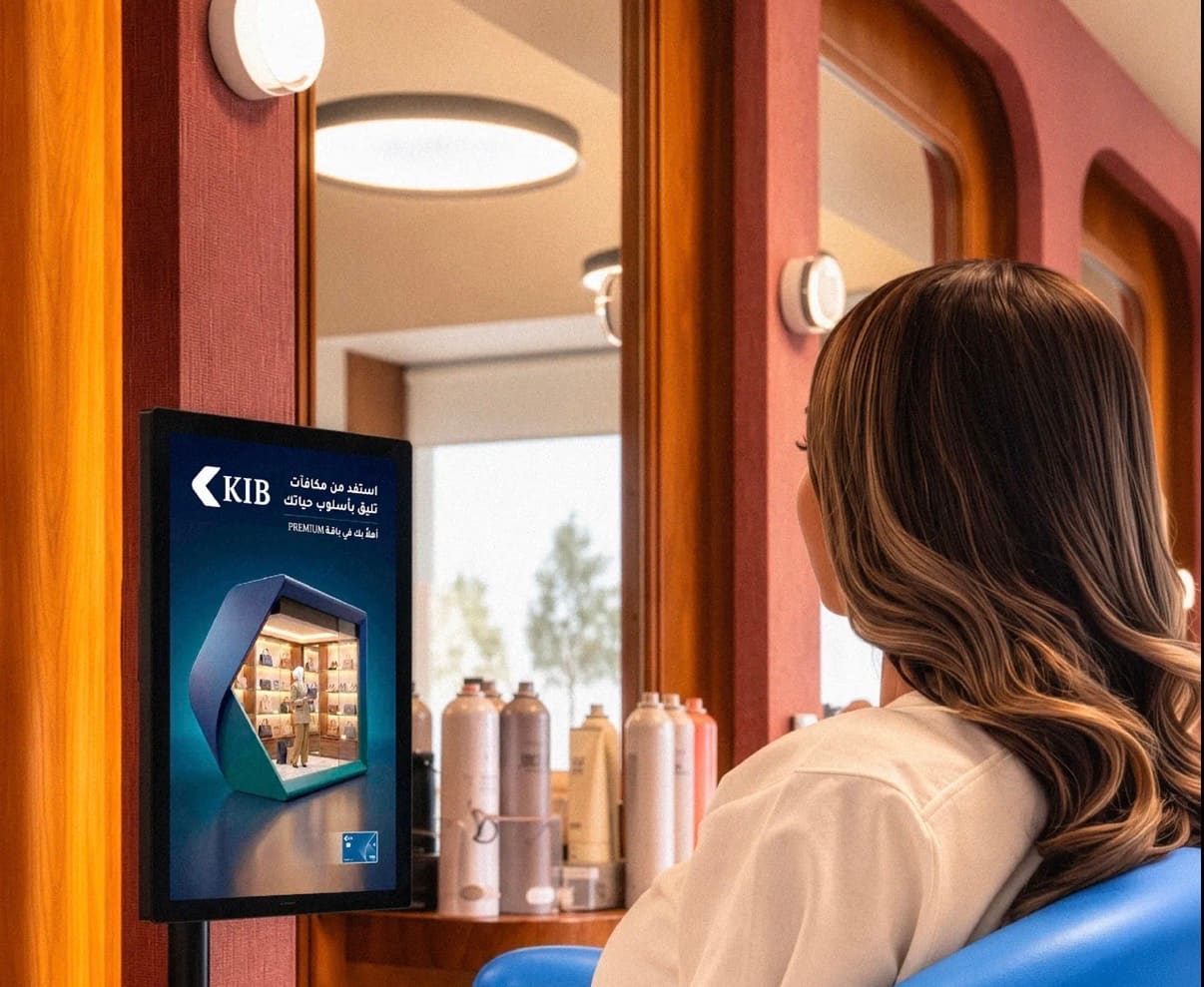 KIB's Premium rewards ad on a standing screen beside the mirror, as a client sits in the chair of a women's salon in Kuwait