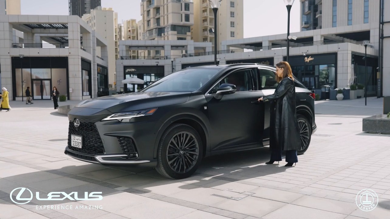 Lexus ad: a woman opening the door of a black Lexus RX in a Kuwait City plaza, signed Lexus, Experience Amazing